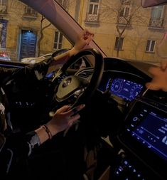 a woman sitting in the driver's seat of a car with her hand on the steering wheel