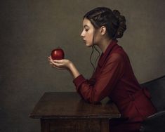 a woman sitting at a desk with an apple in her hand