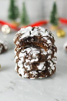 chocolate crinkle cookies stacked on top of each other with christmas decorations in the background