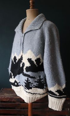 "A pale blue, black and off-white knitted wool Cowichan style sweater by Longhouse, dating from the 1980s. Noted flaws - some very light marking at the collar area, some light piling throughout - please see photos. Great condition otherwise, thick, soft, heavyweight 100% wool, mountain scene and cabin design, original zipper runs smoothly, unlined, two hand pockets, excellent quality, larger size, perfect for keeping cosy on summer evenings, or as a thick, warm layer in cooler weather.  Pit to p Cabin Sweater, Brown Shawl, Cowichan Sweater, Tree Sweater, Ivy League Style, Knit Shawl, Chunky Cardigan, Mountain Scene, Cabin Design