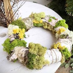 a wreath made out of branches and moss sits on top of a white piece of wood