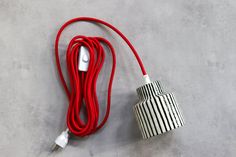 a red cord connected to an electronic device on a gray surface with a black and white striped design