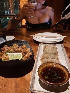 a woman sitting at a table with food and drinks