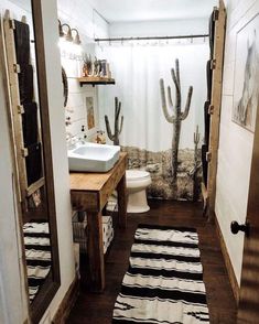 a bathroom with a cactus shower curtain next to a white sink and wooden flooring