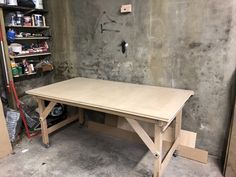 a workbench in a garage with tools on the floor and shelves behind it