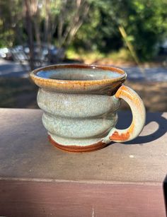 a stack of three cups sitting on top of a wooden table next to a tree