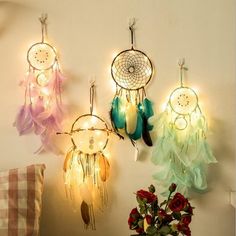 three dream catchers are hanging on the wall next to a vase with flowers in it