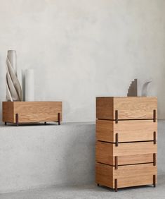 two wooden boxes sitting next to each other on top of a cement floor near vases