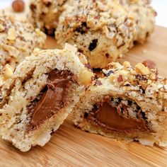 several cookies with chocolate frosting and nuts on a wooden cutting board, cut in half