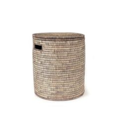 a large woven basket with black handles on the bottom and sides, sitting against a white background