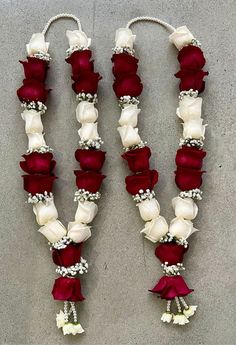 two red and white flowers are attached to the same necklaces on a gray surface