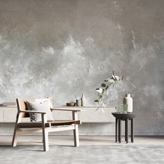 two chairs and a table in front of a wall with a plant on it,