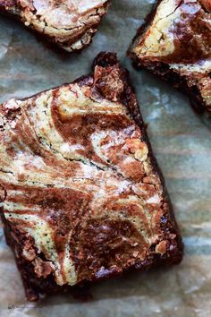 some brownies that are sitting on a piece of parchment paper with chocolate swirl toppings