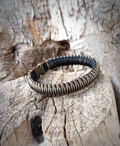 a black and silver bracelet sitting on top of a piece of wood