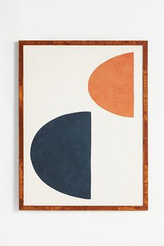 an abstract painting with blue, orange and white shapes on it's surface in a wooden frame