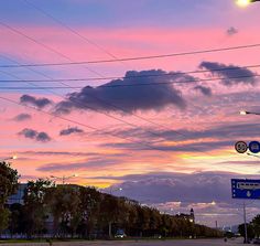 the sky is pink and purple as it sets on an overcast day with power lines in the foreground