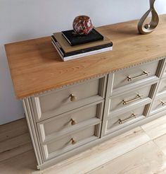 a wooden dresser with two books and a vase sitting on it's sideboard