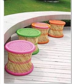 colorful wicker stools are lined up on a white wooden deck in an outdoor setting