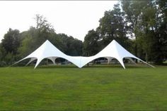 two large white tents sitting on top of a lush green field