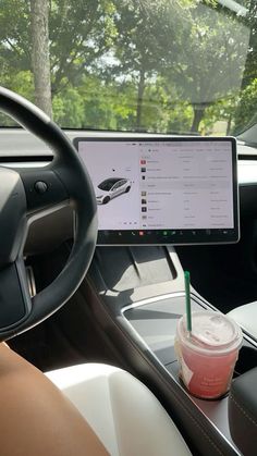 a woman is sitting in the driver's seat of a car with a cup of coffee