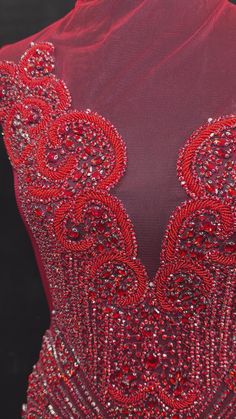 the back of a red dress with beading and sequins on it's chest