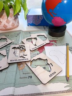 several wooden coasters on top of a map with a pencil and plant in the background