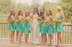 a group of women standing next to each other in front of a fence with sunflowers