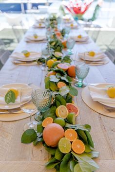 a long table is set with fruit and greenery