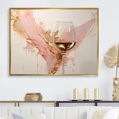 a white couch sitting next to a painting with a glass of wine on top of it