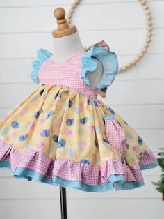 Girls Easter Dress This adorable Easter dress features a fun Easter Egg print with pretty pink gingham. Pockets for putting treasures in! Back is Elastic and ties in a pretty bow. This is a vintage length dress. Bloomers can be added on! Easter Dresses With Ruffles And Short Sleeves, Sweet Gingham Dress With Ruffles, Playful Cotton Dress For Picnic, Playful Gingham Dress With Ruffles, Playful Easter Dresses For Playtime, Multicolor Cotton Dress For Easter, Playful Gingham Dress For Playtime, Playful Gingham Dress For Spring, Spring Playful Gingham Dress