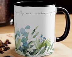 a coffee mug sitting on top of a wooden table next to a spoon and cup