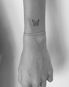 a woman's wrist with a butterfly tattoo on the left side of her arm