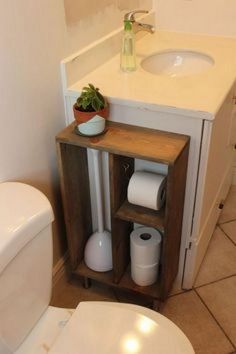 a white toilet sitting next to a wooden cabinet in a bathroom under a sink and mirror