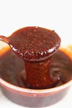 a spoon full of sauce sitting in a bowl