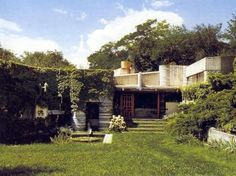 the house is surrounded by greenery and has stairs leading up to it's roof