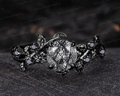 an intricately designed ring with white stones on it's center and leaves in the middle