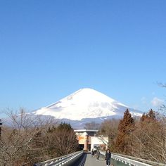 two people walking on a bridge with a mountain in the background