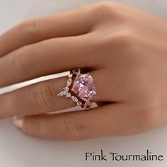 a woman's hand wearing a pink tourmaline ring with diamonds on it