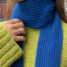 a close up of a person wearing a blue and yellow sweater with a ring on their finger