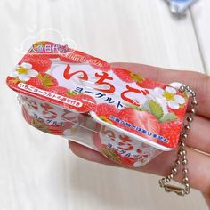 a hand holding a small plastic container filled with yogurt and strawberries in it