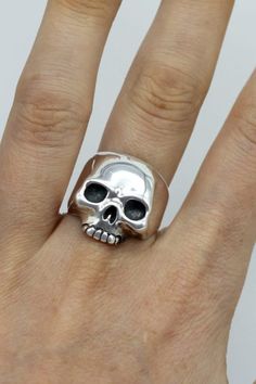 Our classic silver skull ring is a staple in your skull ring collection, a great look on both men and women. Originally hand carved from wax, now cast into silver, we size each one of our skull rings by hand to fit you perfectly. Each and everyone of our rings are finished by hand with as much attention as the next. ⸸ Metal: Hallmarked Sterling Silver⸸ Weight: approximately 14 g⸸ Handcrafted in: 10 - 15 working days If you need the item sooner please email and we will accomodate where possible. Classic Skull Ring As Gift, Sterling Silver Skull Ring In Punk Style, Hand-cast Skull Ring For Gift, Silver Skull Ring Collectible, Hand Cast Sterling Silver Skull Ring, Punk Sterling Silver Skull Ring, Unique Silver Skull Ring Hallmarked, Sterling Silver Hallmarked Skull Ring Collectible, Dallas Winston