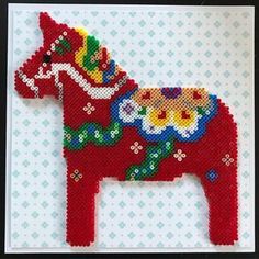 a red beaded horse with flowers on it's body is shown in front of a blue and white background