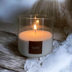 a lit candle sitting on top of snow next to a piece of wood with the word mash written in it