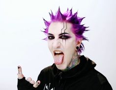 a man with purple hair and piercings making a face