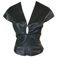 Azzedine Alaia Sexy Cutout Leather Top Black Alaïa leather top with tonal stitching throughout, cap sleeves, plunging neckline and hook-and-eye closures at back. All Eyes on Alaïa For the last half-century, the world’s most fashionable and adventuresome women have turned to Azzedine Alaïa for body-enhancing clothes that give them beauty, sensuality, and confidence, thanks to the meticulous craftsman’s peerless adulation of the female form. Amy Fine Collins unravels the evolution of the fabled Pa Designer Fitted Blouse For Night Out, Luxury Fitted Evening Tops, Designer Fitted Evening Tops, Elegant Leather Tops For Night Out, Elegant Leather Tops For Formal Occasions, Elegant Leather Formal Tops, Elegant Formal Leather Tops, Elegant Leather Party Tops, Luxury V-neck Evening Top