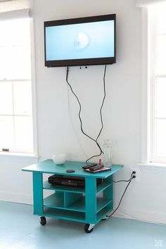 a flat screen tv mounted to the side of a wall above a small blue table