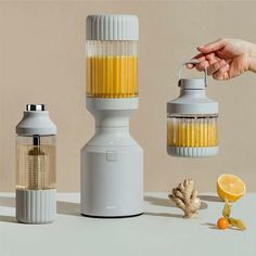 a person is holding an orange juicer next to two lemons and a blender