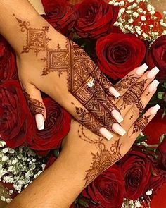 two hands with henna tattoos on them and red roses in the backgroud