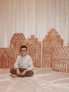 a man sitting on the floor in front of gingerbread houses and windows with lights