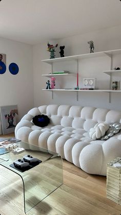 a large white couch sitting on top of a wooden floor next to a glass table